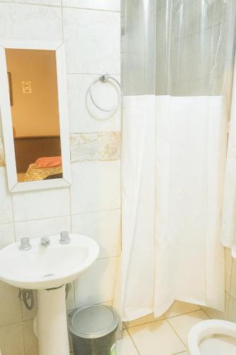 a bathroom with a sink and a mirror at ECONÔMICA AR ESTACIONAMENTO e CAFÉ in Canoas