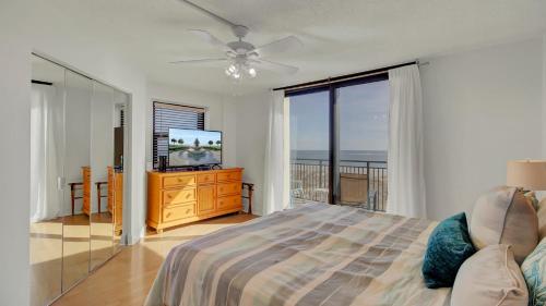 a bedroom with a bed and a television with a balcony at 401 A Shipwatch by AvantStay Beachfront Condo w Community Pool Access in Isle of Palms
