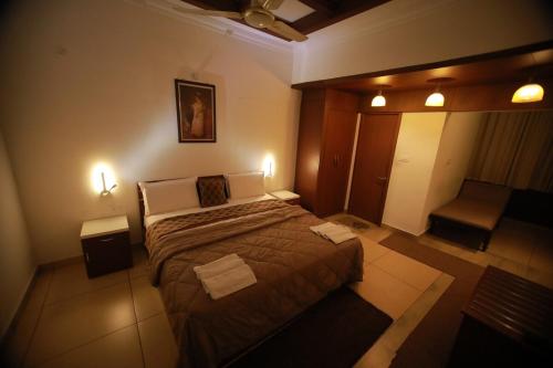a bedroom with a large bed and two lights at Rampart Apartments in Cochin