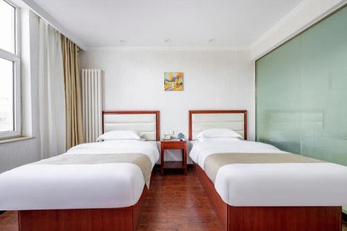 a row of three beds in a room at GreenTree Inn Yinchuan Pedestrian Street East Liqun Street Express Hotel in Yinchuan
