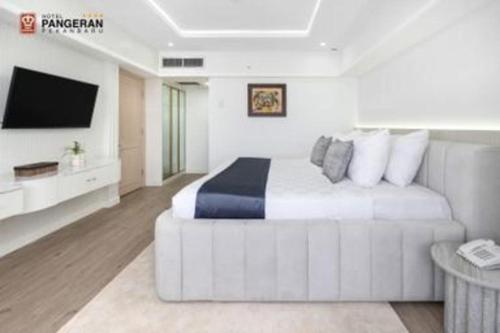a white bedroom with a bed and a tv at Hotel Pangeran in Pekanbaru