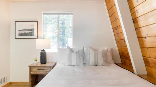 a bedroom with a white bed with a window at Chickaree by AvantStay A-Frame w Mountain Views in Tahoe City