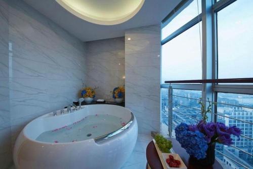 a bathroom with a tub and a large window at New Century Hotel Putuo Zhoushan in Zhoushan