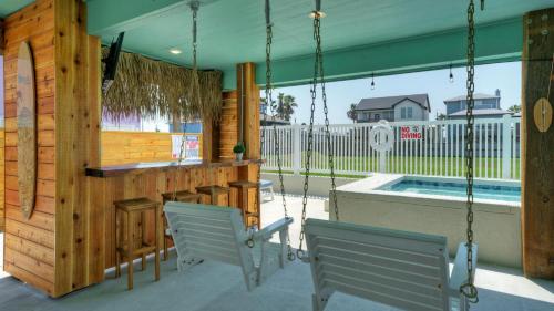 a porch with a bar and chairs and a swimming pool at Private Pool Free Golf Cart 3 Blocks to Town Tequila Tides by AvantStay in Port Aransas