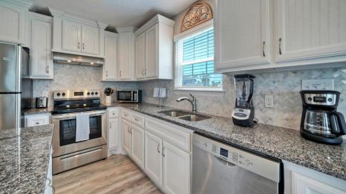 a kitchen with white cabinets and marble counter tops at Private Pool Free Golf Cart 3 Blocks to Town Tequila Tides by AvantStay in Port Aransas