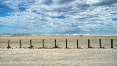 a fence on a beach with the ocean at Private Pool Free Golf Cart 3 Blocks to Town Tequila Tides by AvantStay in Port Aransas