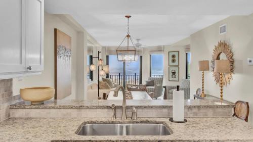 a kitchen with a sink and a living room at 303A Shipwatch by AvantStay Ocean View Shared Pool Boardwalk to Beach in Isle of Palms