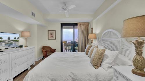 a white bedroom with a bed and a television at 303A Shipwatch by AvantStay Ocean View Shared Pool Boardwalk to Beach in Isle of Palms