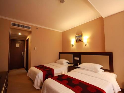 a hotel room with two beds with white sheets at Dalian Bohai Pearl Hotel in Dalian