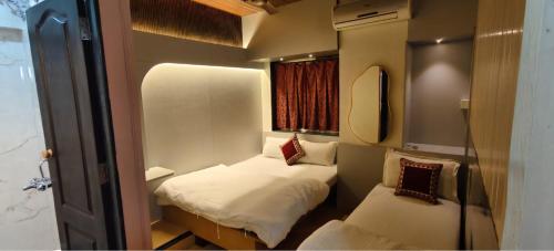 a small room with two beds and a mirror at Hotel Regal Plaza in Mumbai