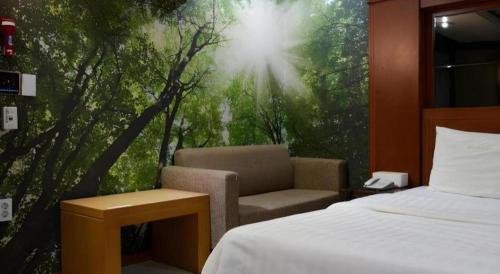 a bedroom with a bed and a chair and a window at Hotel Head-One in Uijeongbu