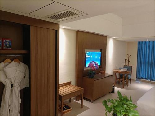 a hotel room with a bed and a table and a television at Da Peng Zhongzhou Hotel in Haikou