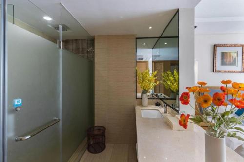 a bathroom with a shower with a vase of flowers at Da Peng Zhongzhou Hotel in Haikou
