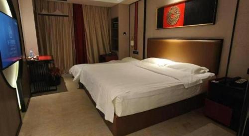 a bedroom with a large bed and a flat screen tv at Yuan Culture Hotel Shenzhen World Shajing in Shenzhen