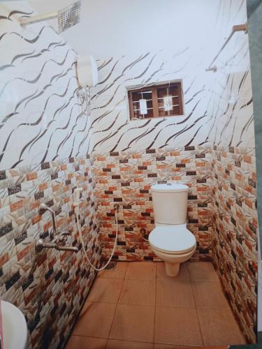 a bathroom with a toilet and a brick wall at Penuel marari homesty in Mararikulam