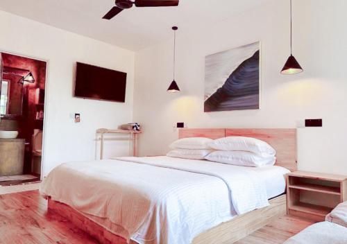 a white bedroom with a bed with white sheets and pillows at Odi Kamadhoo in Kamadhoo