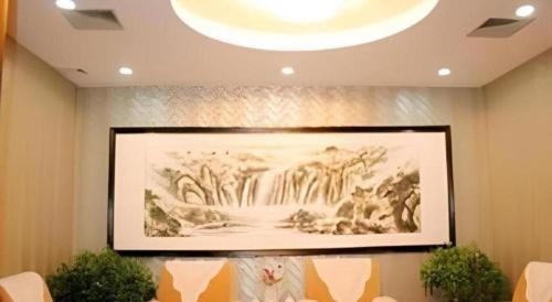 a large painting on a wall with chairs in a room at Zaozhuang Hotel in Zaozhuang