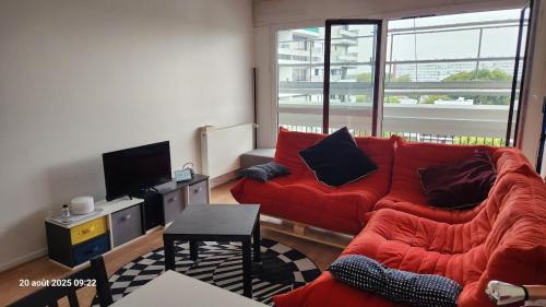 CourcouronnesにあるChambre 1 Personneの赤いソファとテレビのあるリビングルーム