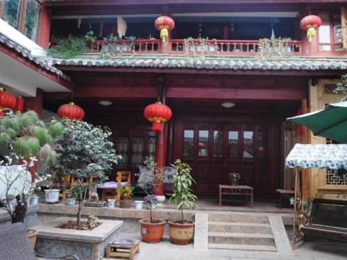 a building with red lanterns and plants in front of it at Lijiang Peach Hostel in Lijiang