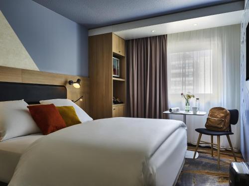 a hotel room with a white bed and a chair at Mercure Paris Gare De Lyon TGV in Paris