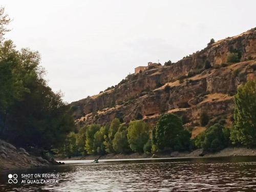 a boat on a river in front of a mountain at La Cerca Entre Hoces-10-20pax-Amplios espacios comunes in Sebúlcor