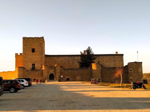 a large castle with cars parked in a parking lot at La Cerca Entre Hoces-10-20pax-Amplios espacios comunes in Sebúlcor