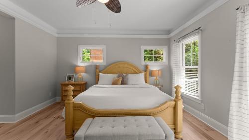 a bedroom with a wooden bed and two windows at Making Waves by AvantStay Sleeps 20 Pool in Westport