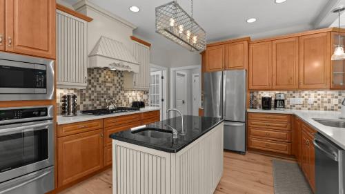 a kitchen with wooden cabinets and a black counter top at Making Waves by AvantStay Sleeps 20 Pool in Westport