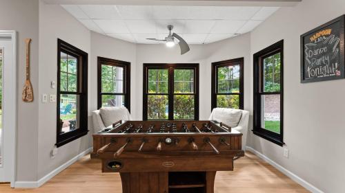 a ping pong table in a room with windows at Making Waves by AvantStay Sleeps 20 Pool in Westport