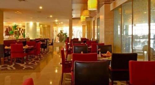 a dining room with red chairs and tables in a restaurant at Grand Metropark Hotel Chongqing in Chongqing