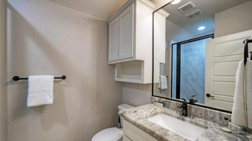a bathroom with a sink and a toilet and a mirror at Pool Access Boat Dock Steps to the Gulf The Pintail by AvantStay in Padre Island
