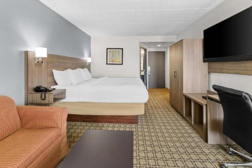 a hotel room with a bed and a couch at Clarion Inn Cranberry Township in Cranberry Township