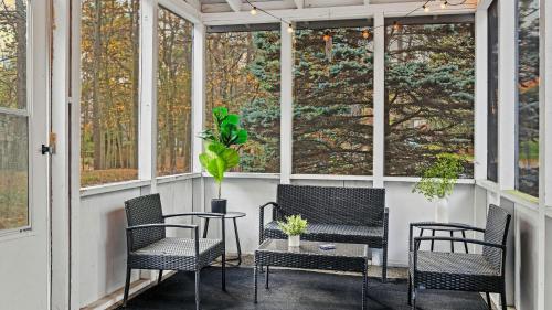 a screened porch with chairs and tables and windows at Mohegan by AvantStay Private Dock Firepit Community Pool Beach in Long Pond