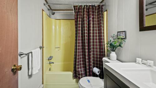 a bathroom with a yellow shower curtain and a toilet at Mohegan by AvantStay Private Dock Firepit Community Pool Beach in Long Pond