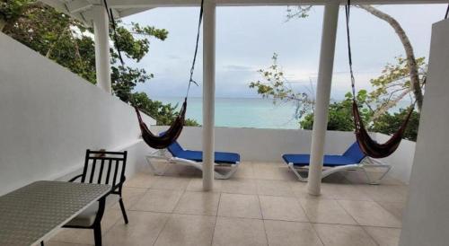 a porch with swings and a view of the ocean at Merrils Deluxe in Negril