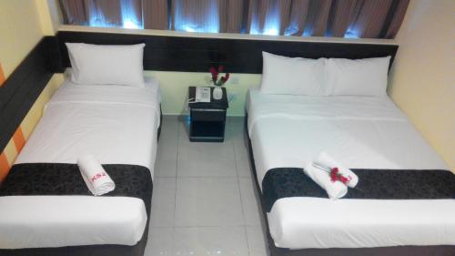 two twin beds in a hotel room with a phone at Sun Inns Hotel Pasir Penambang (KS Botanic) in Kuala Selangor