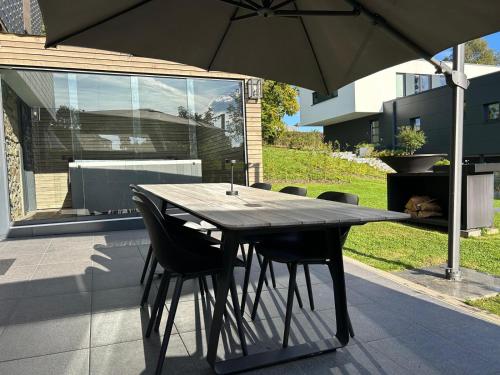 a wooden table with chairs and an umbrella on a patio at Hyronimus House in Amblève
