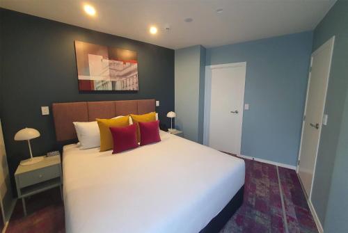 a bedroom with a large white bed with colorful pillows at La Quinta by Wyndham Parnell Auckland in Auckland