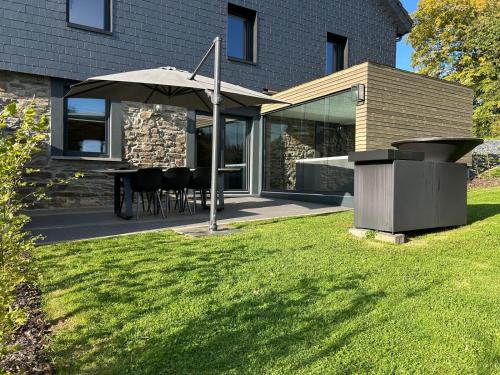 a patio with a table and an umbrella in a yard at Hyronimus House in Amblève