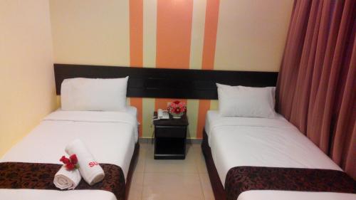 two beds in a hotel room with towels on them at Sun Inns Hotel Pasir Penambang (KS Botanic) in Kuala Selangor