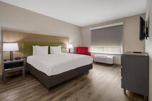 a bedroom with a large white bed and a red chair at Country Inn & Suites by Radisson, Goldsboro, NC in Goldsboro