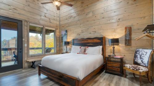 ガトリンバーグにあるRambling Ridge Lodge by AvantStay Endless Amenities Fun Indoor Pool Hot Tub A Arcade Game Roomの木製の壁のベッドルーム1室、ベッド1台、椅子が備わります。