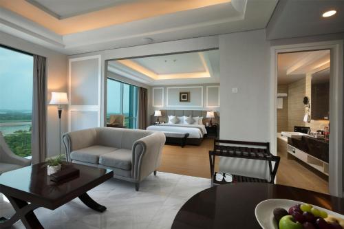 a living room with a bed and a room with a table at Wyndham Panbil Batam in Batam Center