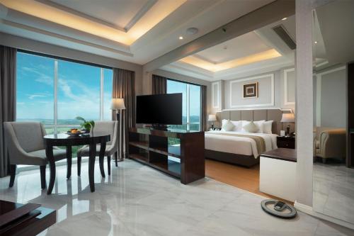 a hotel room with a bed and a desk with a television at Wyndham Panbil Batam in Batam Center