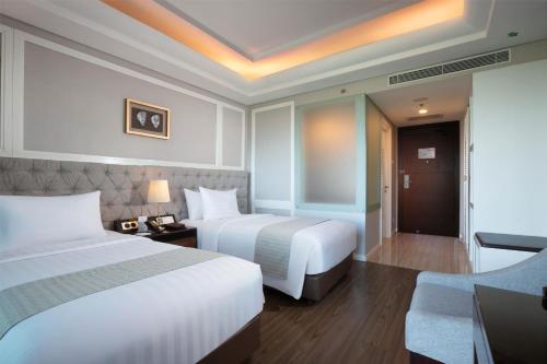 a hotel room with two beds and a couch at Wyndham Panbil Batam in Batam Center