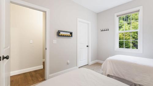 a white bedroom with two beds and a window at Fairview Vista by AvantStay 10 Mins to Asheville in Fairview