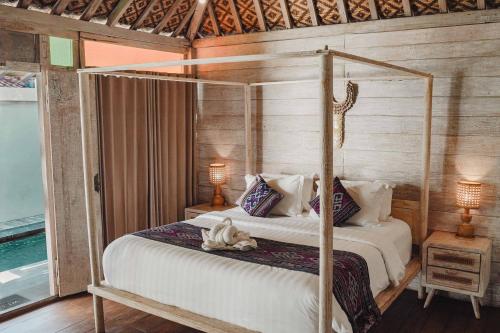 a bedroom with a four poster bed with a dog on it at Java Wood in Gili Trawangan