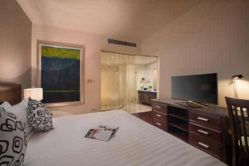 a bedroom with a bed with a television and a window at Fraser Suites Hanoi in Hanoi