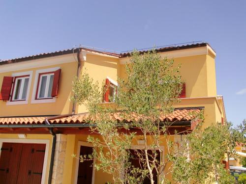 a yellow house with a tree in front of it at Oliva Holiday Apartment in Banjole
