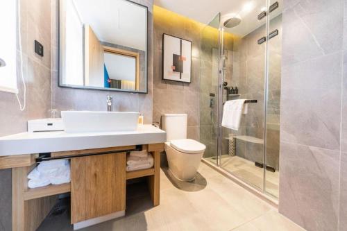 a bathroom with a sink and a toilet and a shower at New Beacon Sunyee SPA Hotel in Wuhan